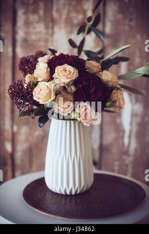 Schöner Blumenstrauß Rosen und Nelken in einer Vase, Vintage-Stil. Elegante Wohnkultur. Stockfoto