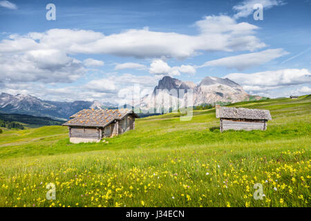 Schöne Aussicht auf die idyllische Bergkulisse der Alpen mit traditionellen alten Chalets und frischen grünen Wiesen an einem sonnigen Tag mit blauem Himmel und Wolken Stockfoto