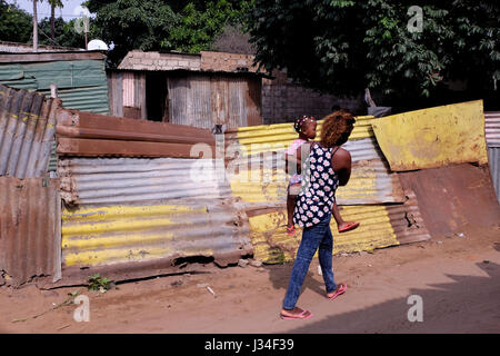 Eine Frau trägt ein junges Mädchen in ihren Armen, als sie durch Barrio da Mafalala geht, einem armen Slum von Maputo, der Hauptstadt von Mosambik Afrika Stockfoto