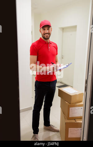 Lieferung Mann mit Boxen und Zwischenablage an Tür Stockfoto