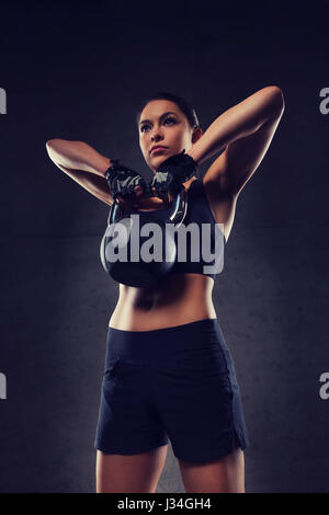 junge Frau, die Muskeln mit Kettlebell in Turnhalle Stockfoto