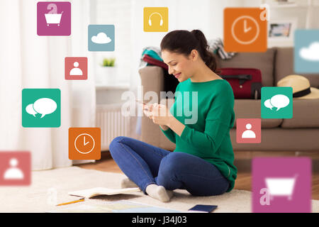 Frau mit Smartphone und Reise-Karte zu Hause Stockfoto