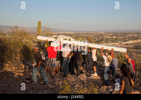 Tucson, Arizona - Teilnehmer in einem jährlichen Karfreitags-Prozession tragen ein großes Kreuz Sentinel Berg hinauf. Die Prozession hält für Stationen von der Stockfoto