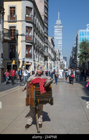 Mexiko-Stadt, Mexiko - 22. April 2017: Drehorgelspieler hält seinen Hut für Spenden auf Avenue Francisco Madero im historischen Viertel. Der Torre Latinoam Stockfoto