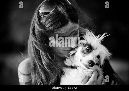 Schöne junge Frau und ihr Chinesischer Schopfhund im Freien. Monochrom. Korn hinzugefügt. Stockfoto