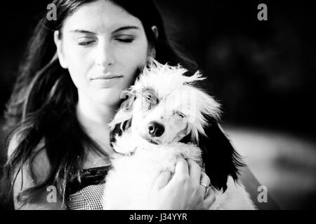 Schöne junge Frau und ihr Chinesischer Schopfhund im Freien. Monochrom. Korn hinzugefügt. Stockfoto