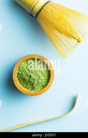 Grünen Matcha Teepulver, Bambusbesen und Bambuslöffel auf blauem Hintergrund. Stockfoto