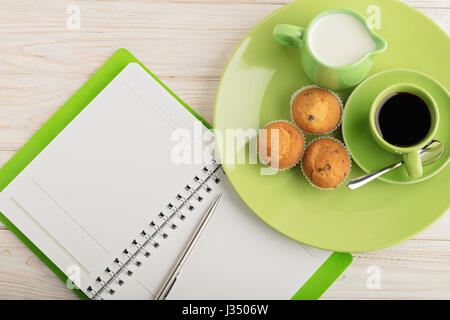 Kaffee mit Milch, Muffins und Notizblock auf hölzernen Hintergrund. Selektiven Fokus. Stockfoto