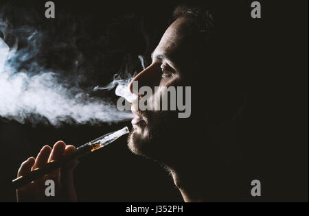 Junger Mann halten und Dampfen eine elektronische Zigarette, e-Cig, Ecigarette. Stockfoto