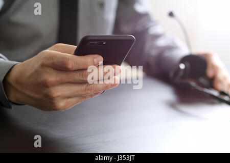 Geschäftsmann mit VoIP-Kopfhörer mit Handy und Konzept Kommunikation-Callcenter auf Schreibtisch aus Holz Stockfoto