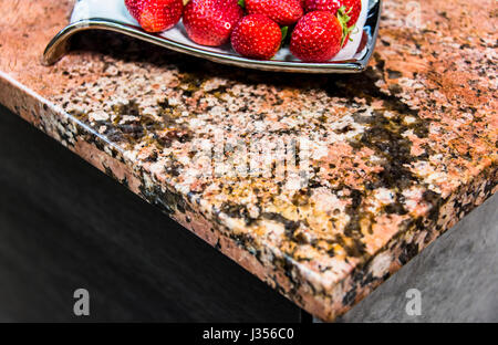 Perspektivische Ansicht des roten Erdbeeren auf moderne rötlicher Granit Arbeitsplatte. Stockfoto