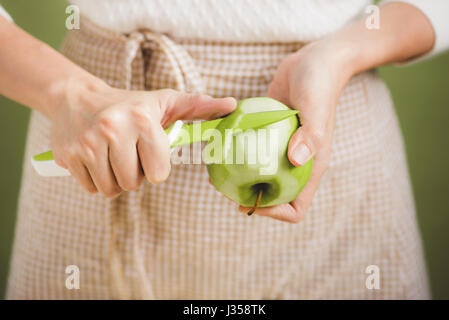 Haus Frau trägt Schürze machen. Schritte der Herstellung Kochen Apfelkuchen. Grünen Apfel schneiden. Stockfoto