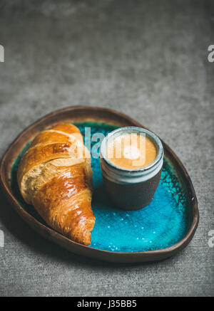 Tasse Espresso und Croissant im blauen Tablett, grauen Hintergrund Stockfoto