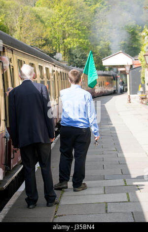 Llangollen Dampfzug Dirigent wehende Flagge an den Fahrer um die Zugfahrt entlang im Sommer beginnen Llangollen, Denbighshire, Wales Stockfoto