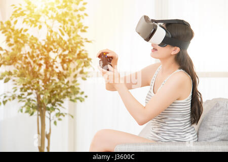 Glückliche Mädchen spielen Videospiele-virtual-Reality Brille in Wohnung. fröhliche Menschen, die Spaß mit neuen Trends-Technologie. Gemischte Rassen asiatischen ch Stockfoto