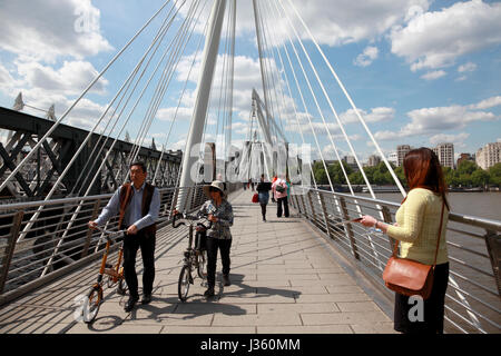 Touristen, die über eine der Brücken Golden Jubilee neben Londoner Southbank Centre Stockfoto