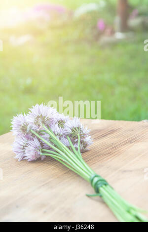 Blume-Schnittlauch gebunden in ein Snop auf ein natürliches Holz Schneidebrett Stockfoto