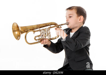 kleiner Junge bläst in eine Trompete vor weißem Hintergrund Stockfoto