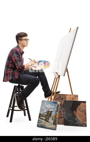 Profil von Schuss von teenage Maler mit Pinsel und Palette Blick auf eine leere Leinwand, die isoliert auf weißem Hintergrund Stockfoto