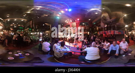 (Anmerkung der Redaktion: Dies ist ein 360-Grad-Foto.)  Menschen hören Live-Musik am Saxophon Pub im Bereich Victory Monument in Bangkok, Thailand. Stockfoto