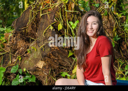 Glückliche Frau mit einem süßen Lächeln auf die Natur mit Bäumen und grünen Hintergrund. Mädchen nach rechts mit Leerzeichen auf der Seite aufgereiht. Weiß Stockfoto