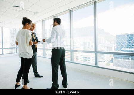 Geschäftsleuten stehen im neuen Büro Raum diskutieren mit Immobilien Makler. Immobilienmakler im Gespräch mit potenziellen Kunden in einem leeren Büro sp Stockfoto