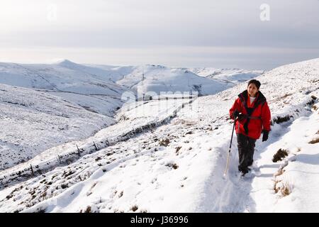 Indische Frau Wandern im Winterschnee, Peak District, UK Stockfoto