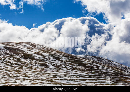 Schneeflecken auf Bergen und flauschigen Wolken an sonnigen Tag Stockfoto