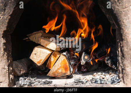 Brennholz brennt in einer alten Lehm Ofen. Helle Flammen und schwarze Asche. Niemand um ihn herum. Stockfoto