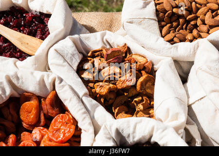 Getrocknete Aprikosen, Äpfel, Rosinen und Mandeln Nüssen in kleine weiße Leinen Säcke auf dem Display zum Verkauf an lokale Lebensmittel-Messe. Niemand um ihn herum. Stockfoto