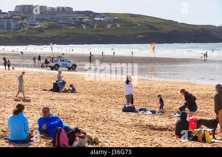 Newquay, Großbritannien. Strandurlauber genießen Sie die Sonne an einem hellen, sonnigen Frühling Nachmittag am Fistral Beach in Newquay. RNLI Rettungsschwimmer Fahrzeug van Menschen Surfer Stockfoto