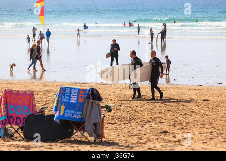 Newquay, Großbritannien. Strandurlauber genießen Sie die Sonne an einem hellen, sonnigen Frühling Nachmittag am Fistral Beach in Newquay. Surfer Schaulustigen Menschen Handtücher Stockfoto