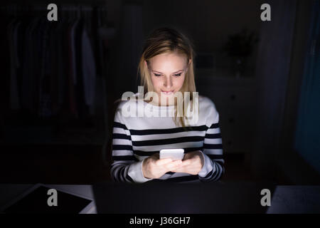 Frau mit Laptop und Smartphone, SMS. Stockfoto
