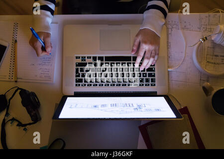 Nicht erkennbare Frau sitzen am Schreibtisch arbeiten am Laptop. Stockfoto