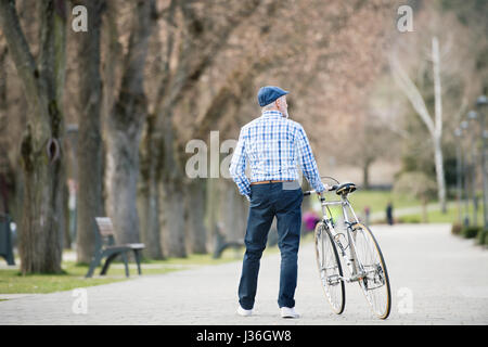 Senior woman in blau kariertes Hemd mit dem Fahrrad in der Stadt. Stockfoto