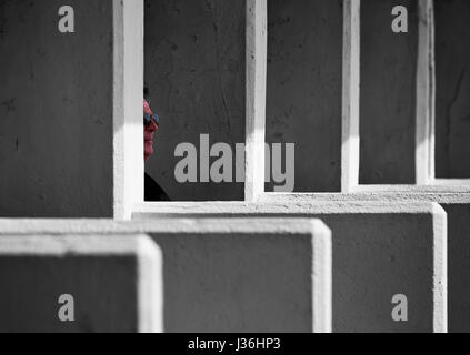 Teilansicht des Gesicht eines Mannes, mit Sonnenbrille, sitzend im Meer Stände bilden ein regelmäßige geometrische Muster durch Perspektive Kompression Stockfoto