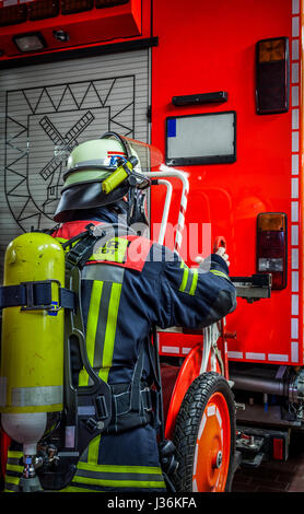 Feuerwehrmann im Einsatz auf dem Einsatzfahrzeug mit Sauerstoffflasche und Atemschutz Maske - HDR Stockfoto