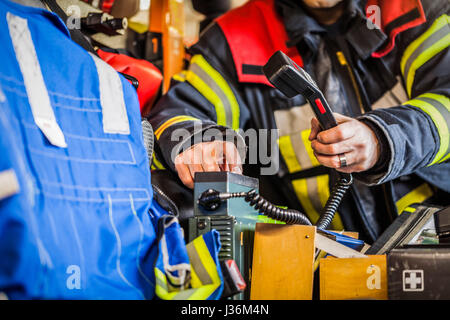 Feuerwehrmann verwendet einen Radioapparat in ein Feuerwehrauto Stockfoto