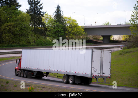 Heavy Duty kraftvolle Rot Big Rig Semi Truck mit Tag cab für lokale Ladung tragen lange trocken van Trailer dreht sich auf der Autobahn von einem anderen Autobahn Ausfahrt Stockfoto