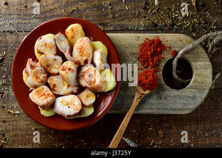 High-Angle Shot von einem Tontopf-Platte mit Pulpo ein la Gallega, eine Rezept von Octopus typisch in Spanien auf Kartoffeln serviert und gewürzt mit Paprika, auf Stockfoto