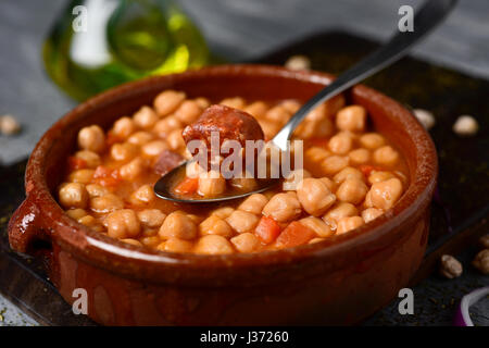 Nahaufnahme von einem Steingut-Schale mit Potaje de Garbanzos, eine spanische Kichererbsen-Eintopf mit Chorizo und Serrano Schinken auf einem rustikalen Holztisch Stockfoto