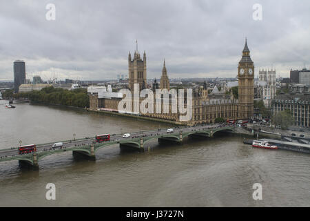 Palast von Westminster genommen vom London Eye an einem grauen Tag in London, big Ben und roten Londoner Busse überquert die Themse auf der Brücke Stockfoto