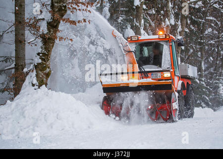 Halter C9700H kommunaler Traktor mit Schneefräse Schneeräumung von Straße im Wald nach starkem Schneefall im winter Stockfoto