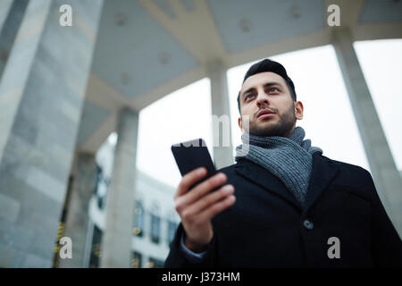 Erfolgreicher Geschäftsmann mit Smartphone in Stadt Stockfoto