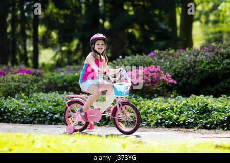 Kinder Reiten Fahrrad. Kind auf dem Fahrrad im sonnigen Park. Kleine Mädchen genießen Radtour auf dem Weg zur Schule an warmen Sommertag. Vorschüler lernen, balan Stockfoto