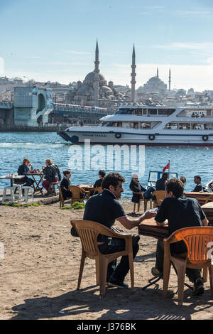 Cafe am Karakoy Waterfront, Blick über das Goldene Horn auf die Yeni-Moschee auf Eminönü und die Skyline von Istanbul. Istanbul, Türkei. Stockfoto