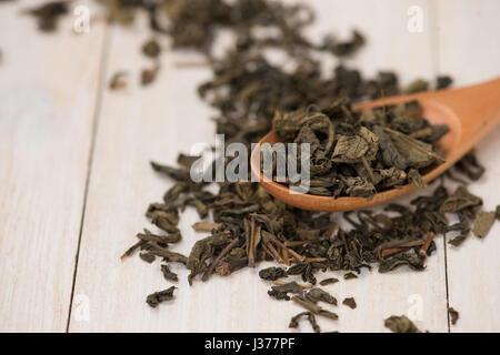 Schwarzer Tee in eine Glasschale und Tee Blätter in Holzlöffel auf schwarzem Stein. Stockfoto