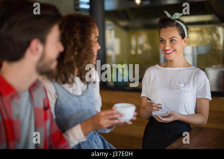 Lächelnd die Bestellungen von Kunden im Restaurant Kellnerin Stockfoto