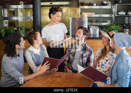 Kellnerin im Gespräch mit Kunden während der Einnahme von Bestellung im restaurant Stockfoto