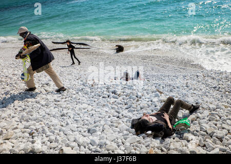 MARINA DI PISA, Italien - Avril 24, 2017: Blick auf das Meer und der Strand mit weißen Kieselsteinen, Menschen nehmen Sie die erste Sonne von der Saison und Farbe Walker in Ma Stockfoto